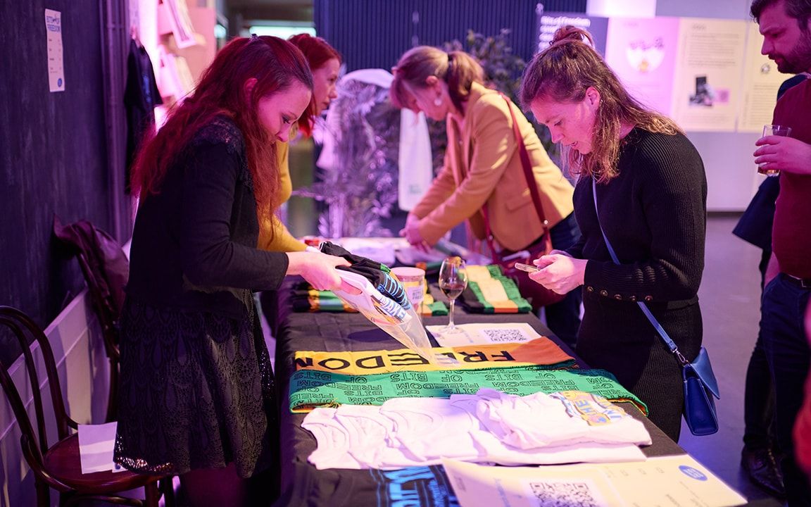foto van tafel met merch en mensen die iets kopen